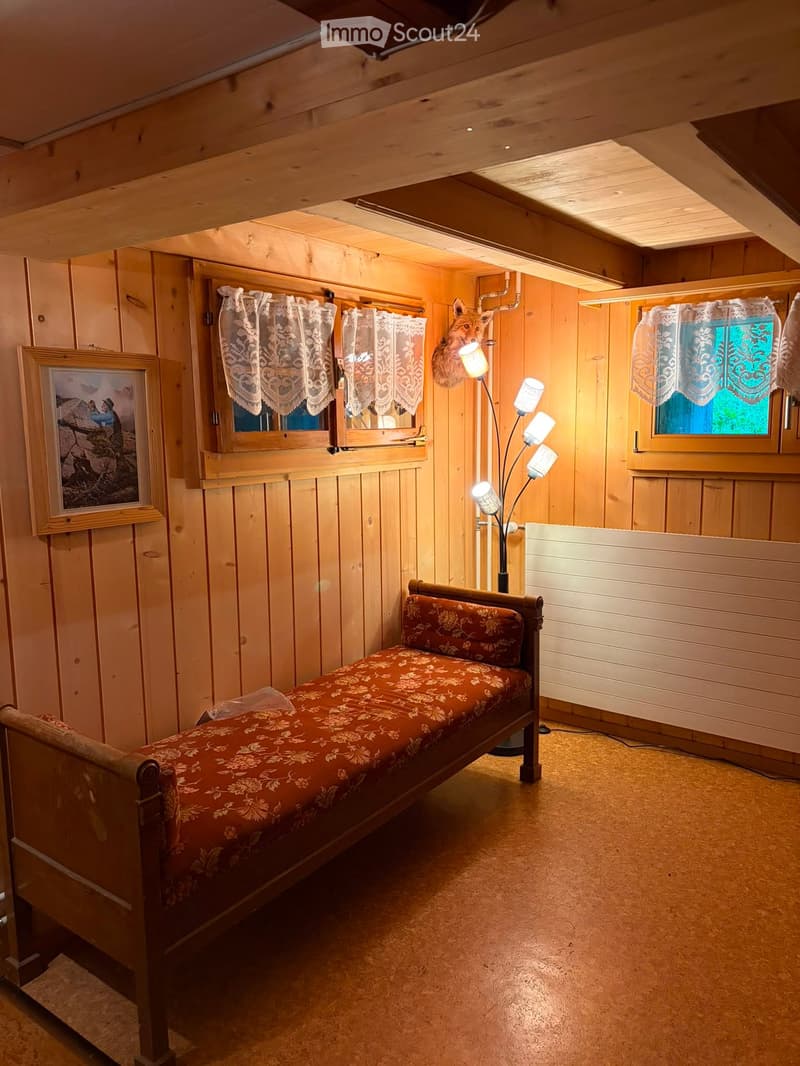 Cozy wooden bedroom with a single bed, floor lamp, and picture frame on the wall.
