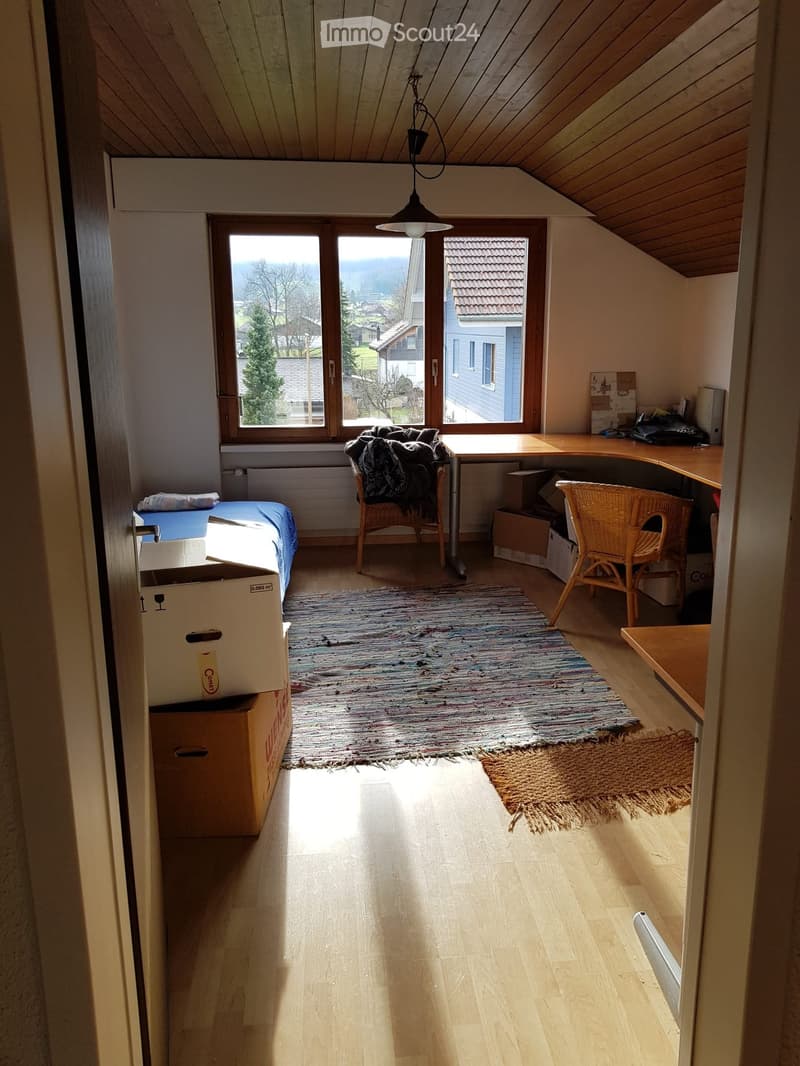 Bright, multi-functional room with wooden floors, a bed, desk, and chairs, featuring large windows with scenic views.