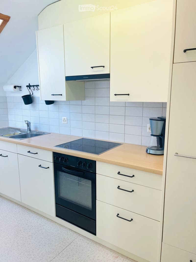 Modern kitchen with white cabinets, stainless steel appliances, and a light wooden countertop.