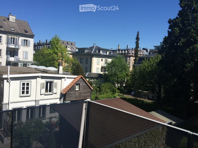 View of a residential area with multiple multi-story houses, trees, and a clear blue sky.