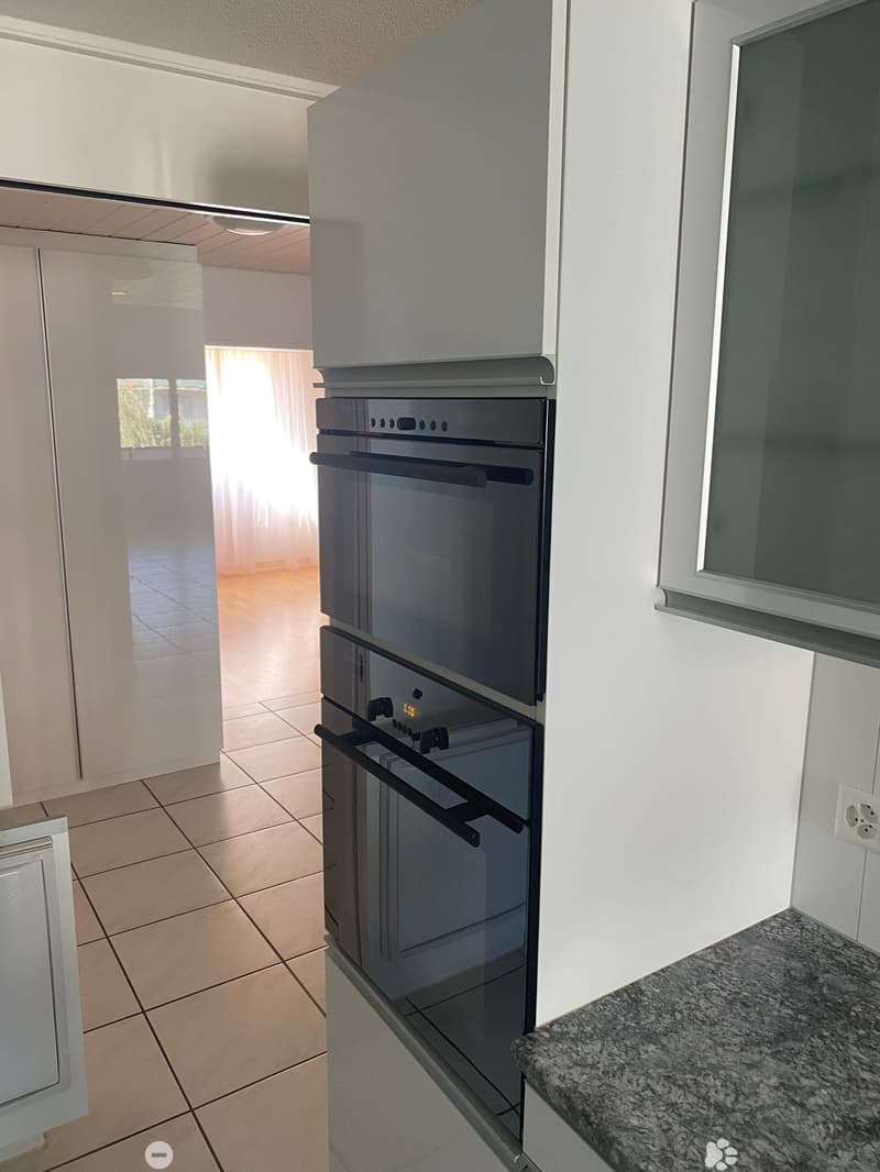 Modern kitchen with white cabinets, tiled floor, granite countertop, and built-in oven.