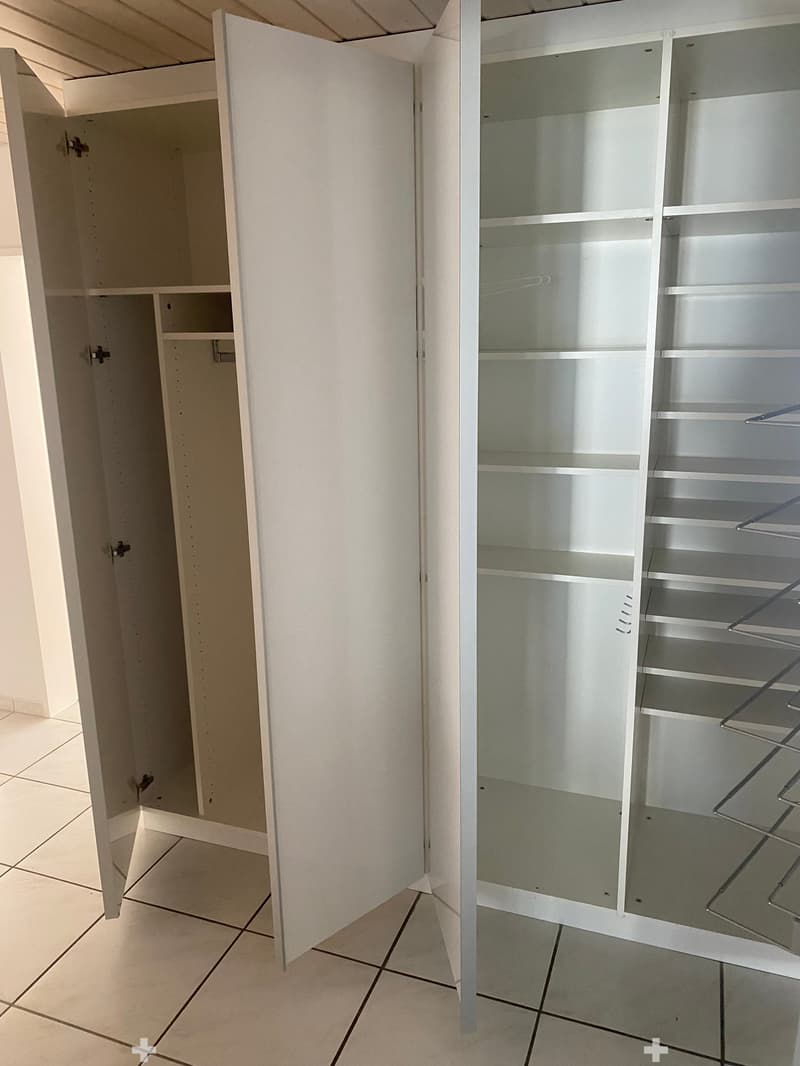 Empty room with white built-in cabinets and shelves, tiled floor, and neutral-colored walls.