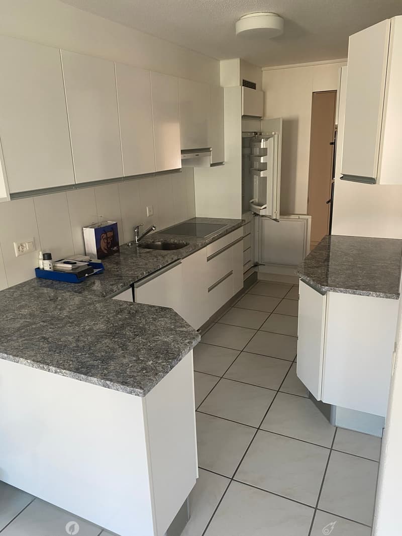 Modern kitchen with white cabinets, granite countertops, and a stainless steel sink.