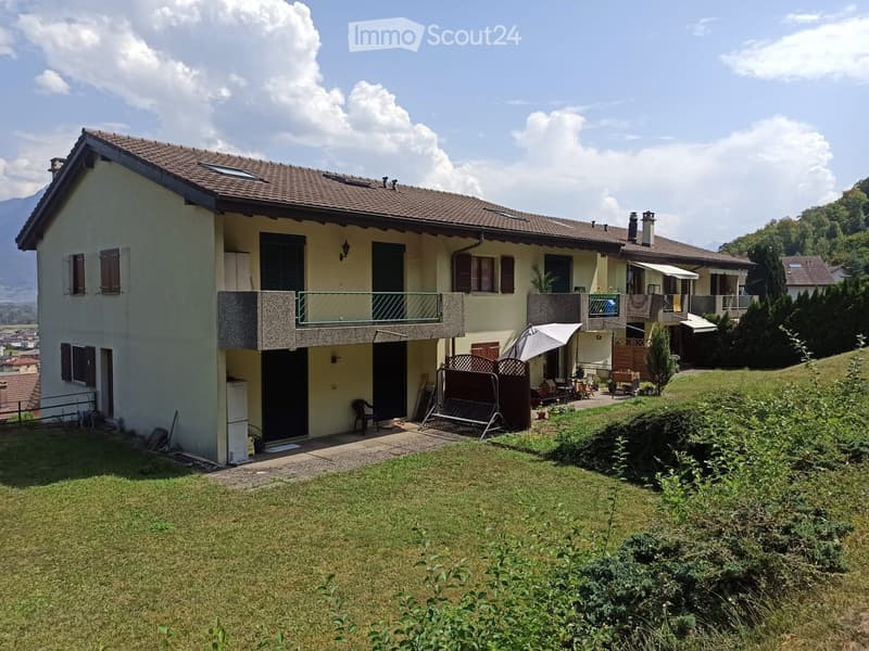 Two-story house with a tiled roof, multiple balconies, and a well-maintained garden with a swing and outdoor furniture.