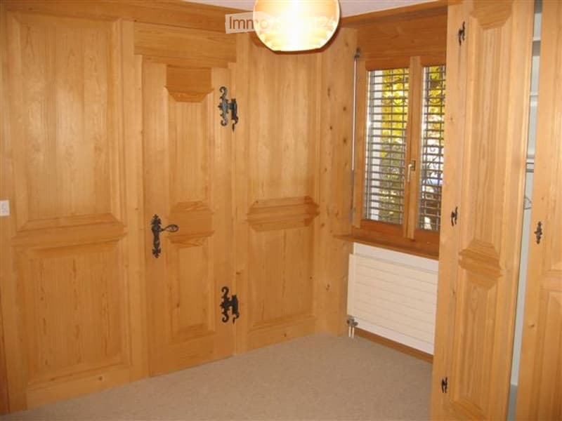 Empty room with wooden panel walls, carpeted floor, and a single window with blinds. No furniture or equipment present.