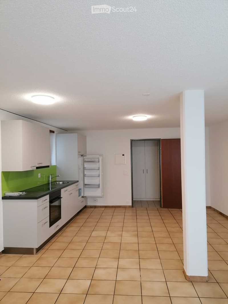 Modern kitchen with white cabinets, green backsplash, tiled floor, and built-in appliances including a sink, oven, and refrigerator.