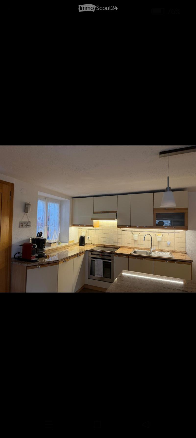Modern kitchen with light-colored cabinets, stainless steel appliances, and a central island with pendant lighting.