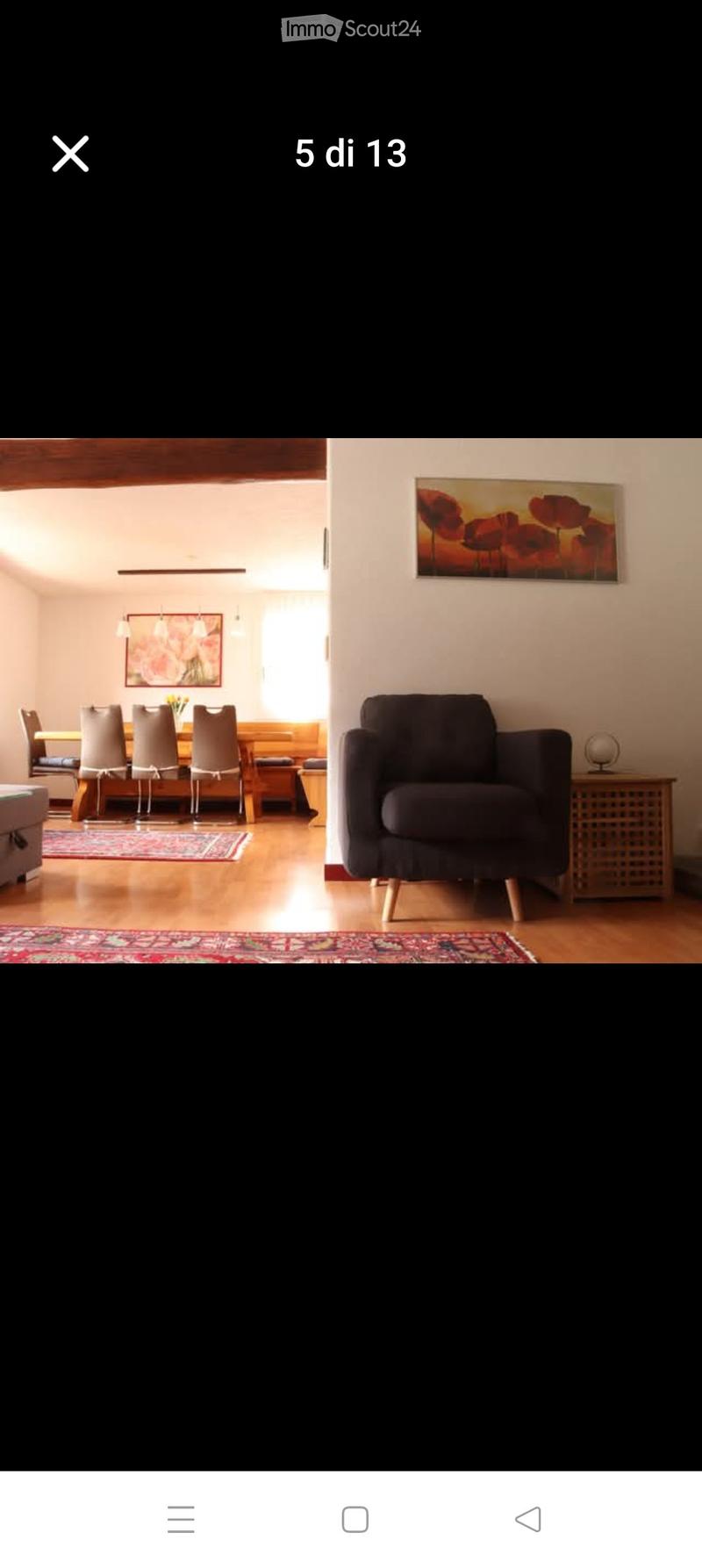A modern living and dining area with a sofa, dining table, chairs, and artwork on the walls.