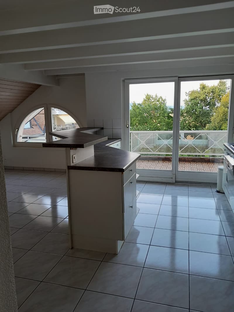 Modern kitchen with a central island, white cabinets, and large windows offering a view of the outdoor area.