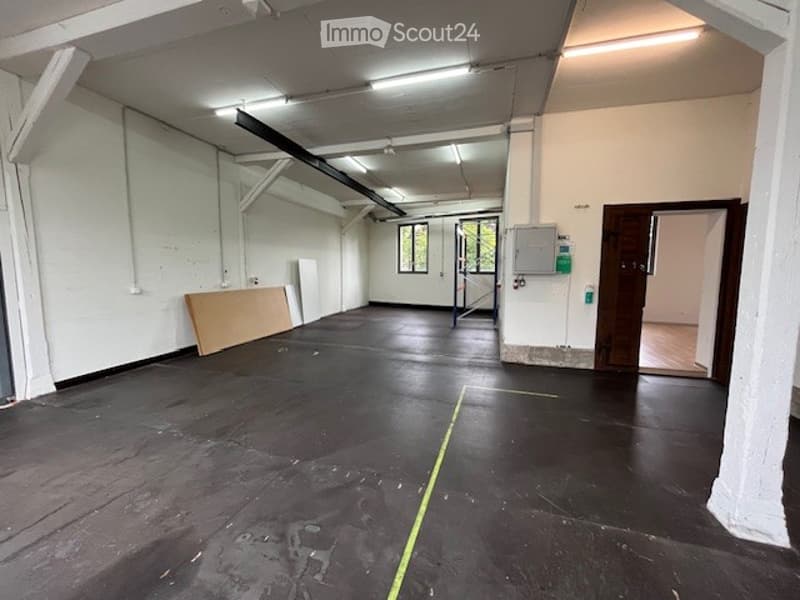 Open room, white walls, black floor, yellow line, large windows, metal poles, metal beam, metal scaffolding
