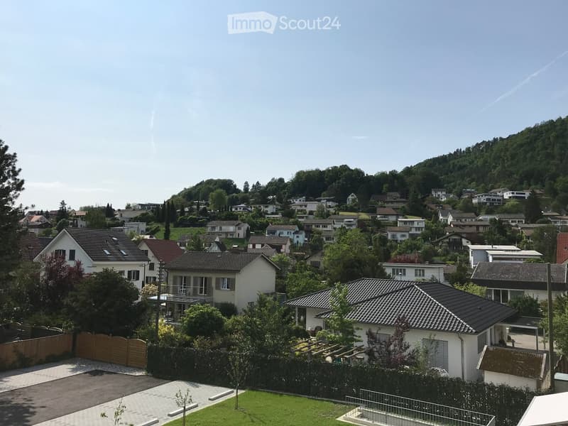 Residential neighborhood with multiple houses, surrounded by greenery and trees, with a clear view of the surrounding landscape.