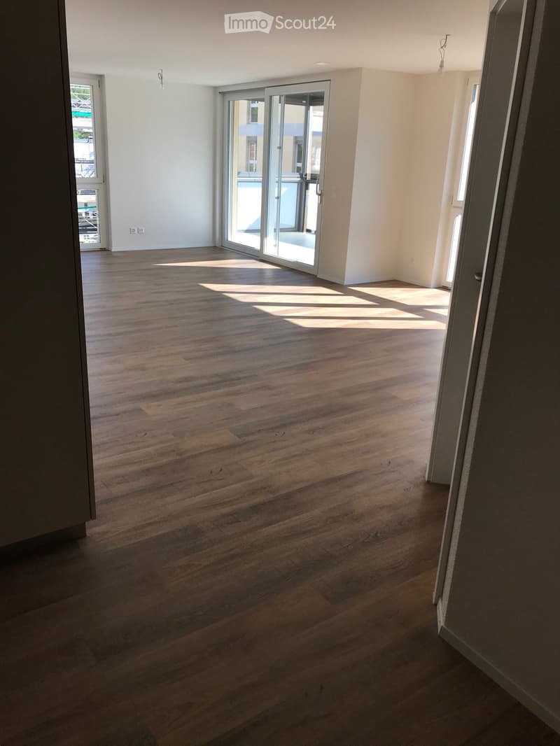 Empty room with wooden flooring, white walls, and large sliding glass doors leading to a balcony.