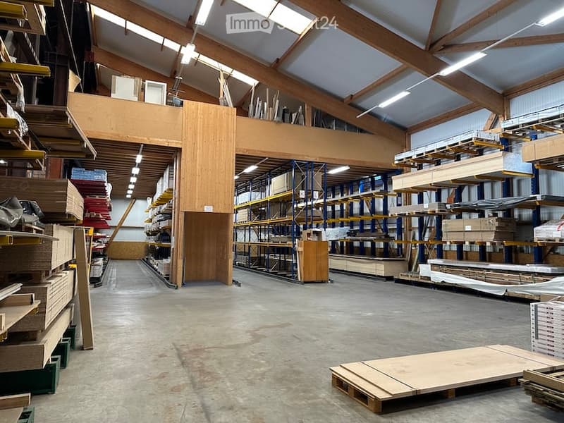 Large industrial-style warehouse with exposed wooden beams, metal shelving units, and various construction materials stored throughout the space.