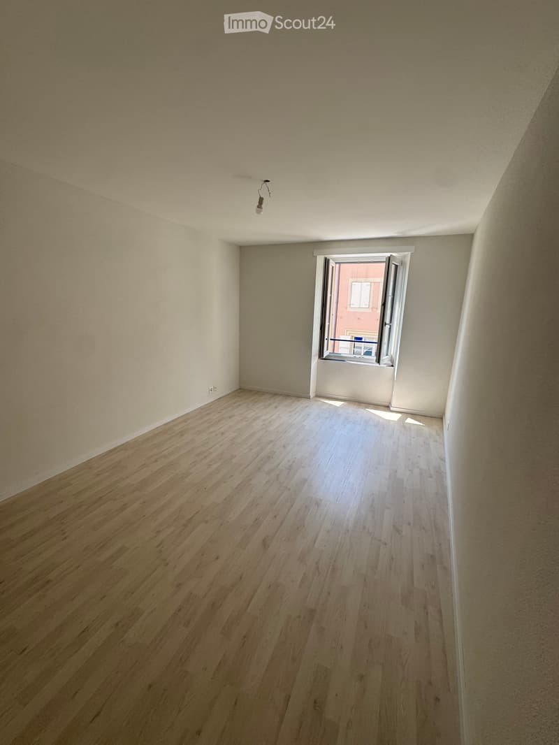 Empty room with wooden flooring, white walls, and a single window with white frame and blinds. No furniture or equipment present.