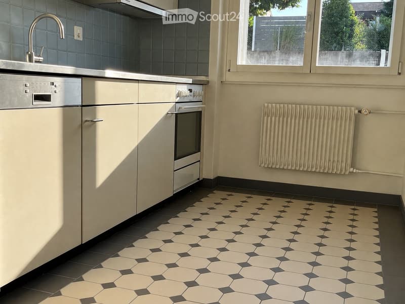 Modern kitchen with white cabinets, stainless steel appliances, hexagonal tile floor, and a radiator on the wall.