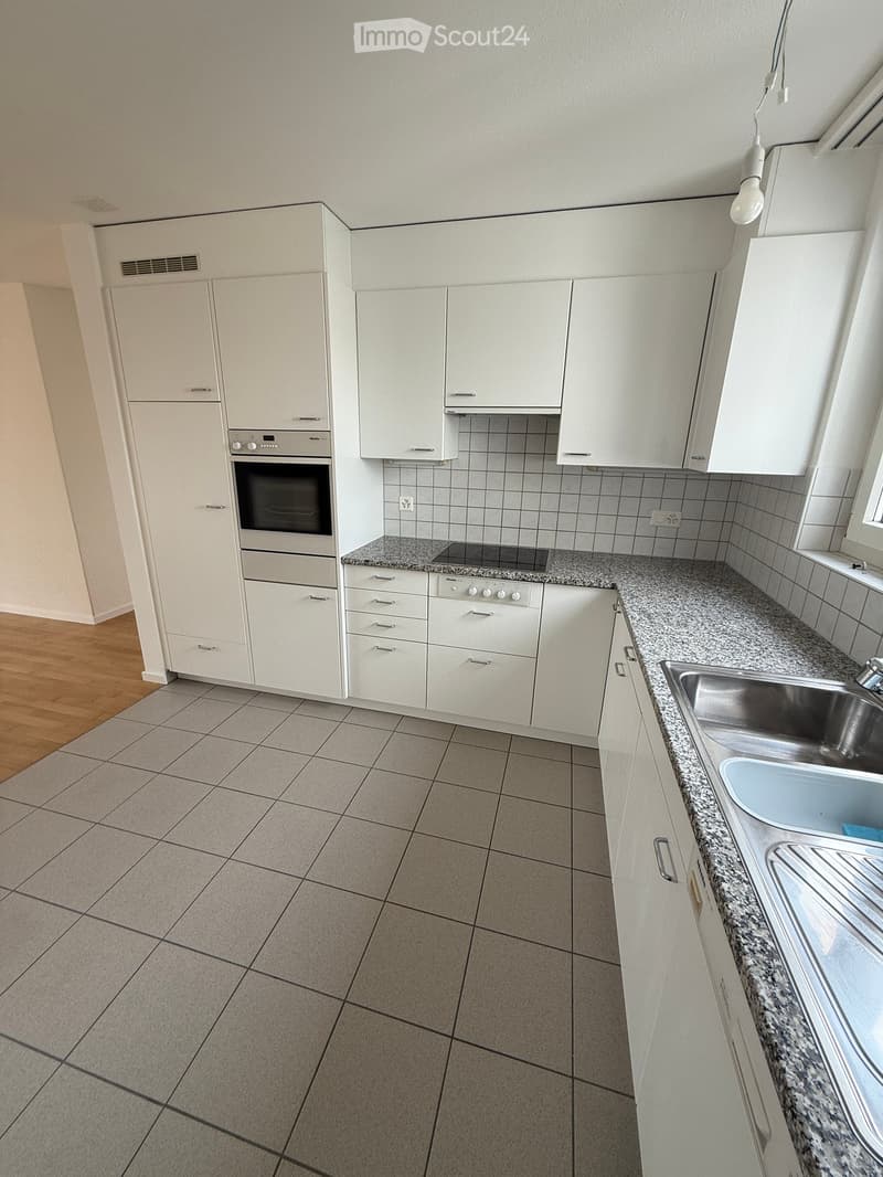Modern kitchen with white cabinets, granite countertops, stainless steel sink, and built-in oven and stove.