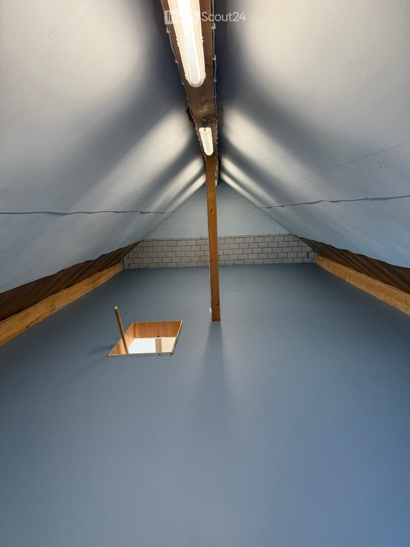 Empty attic space with wooden beams, slanted ceilings, and minimal built-in wooden platforms.