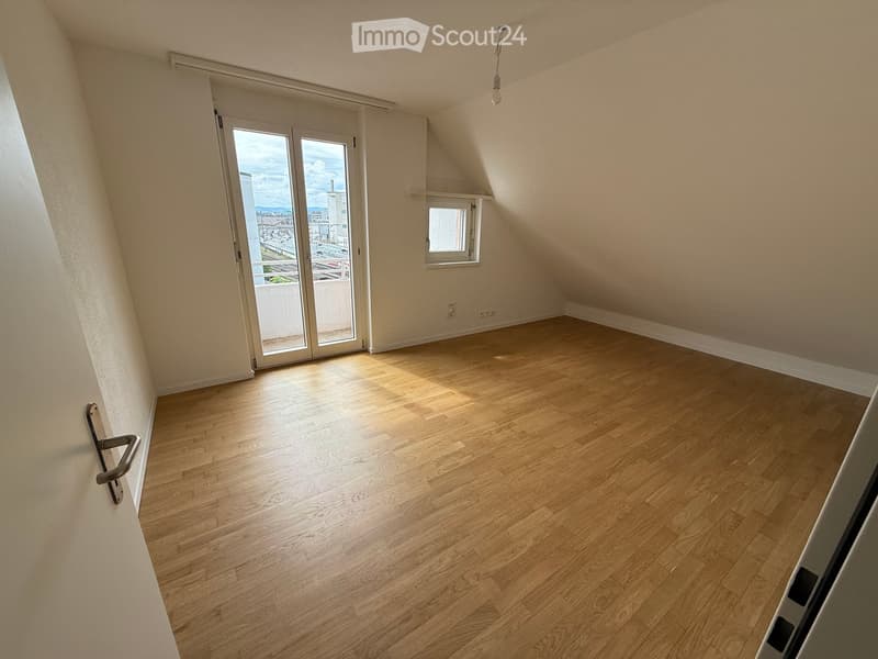 Empty room with wooden flooring, large window, and sliding glass door leading to a balcony.