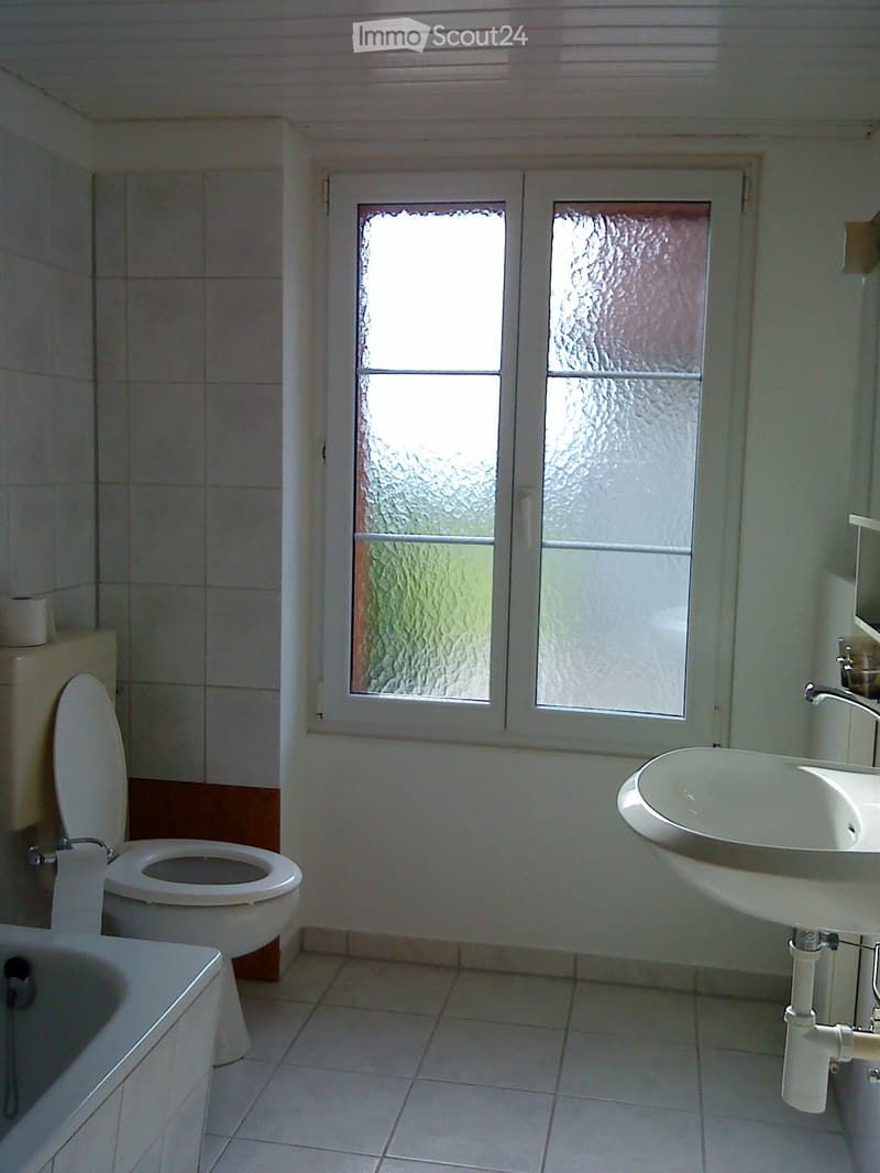 White toilet, bathtub, double sink, white tile walls, window