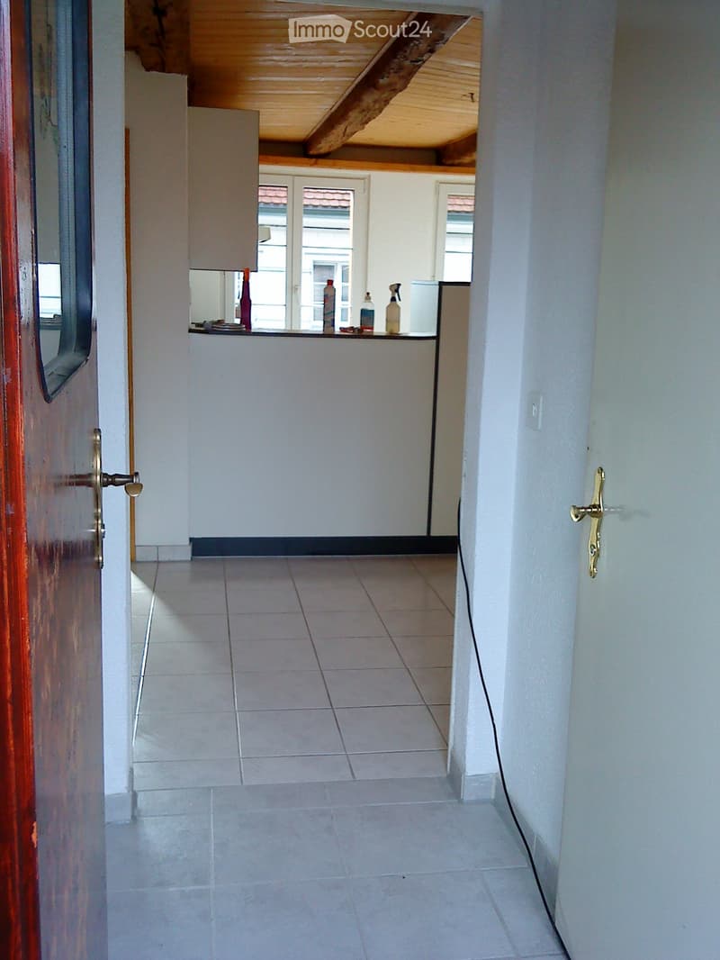 tiled floor, open doorway, wooden beam on ceiling, counter with bottles