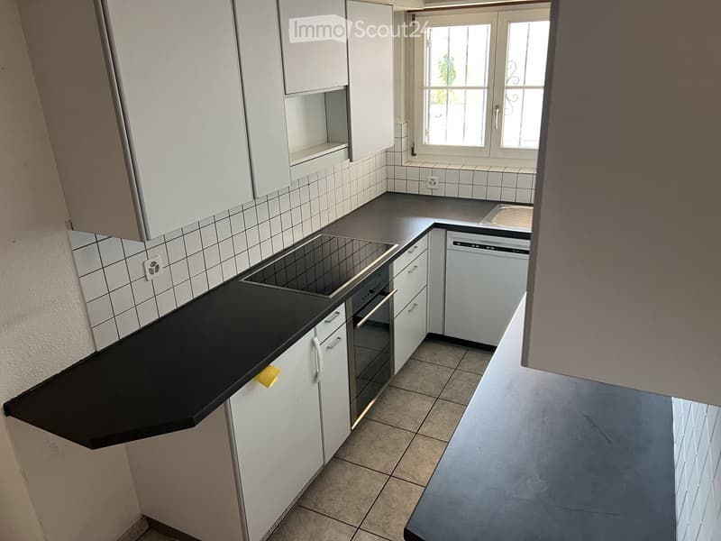 Modern kitchen with white cabinets, black countertops, and built-in appliances including an oven and dishwasher.