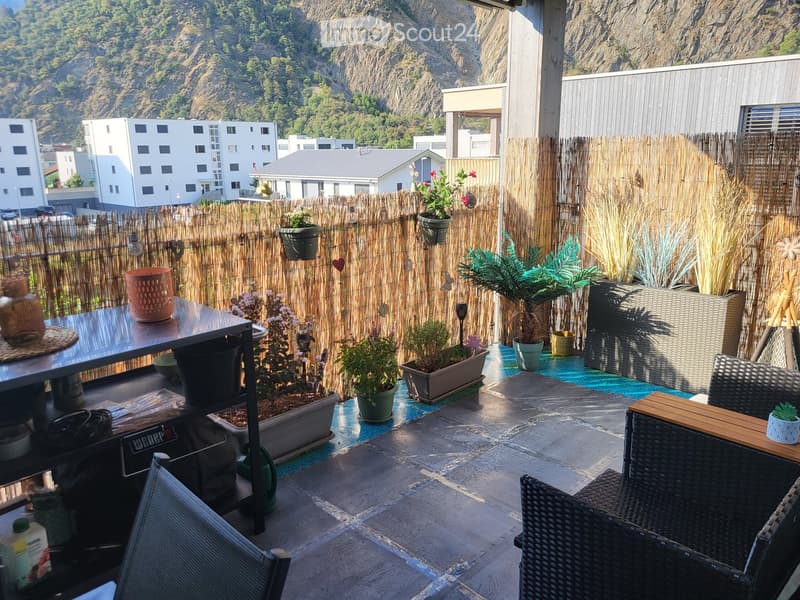 Balcony with a bamboo privacy screen, potted plants, and outdoor furniture including a table and chairs.