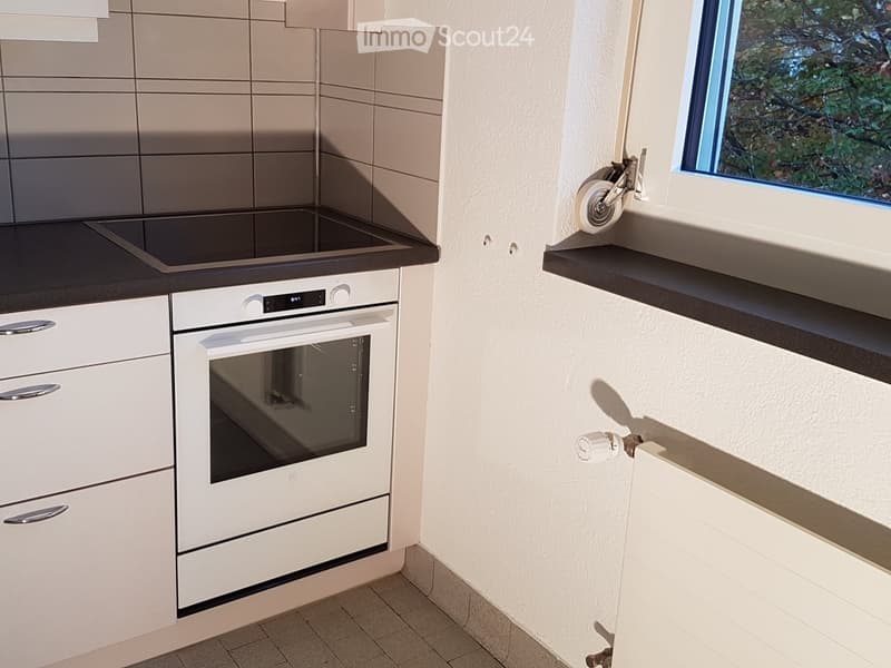 modern kitchen, white appliances, black countertop, white cupboards, window