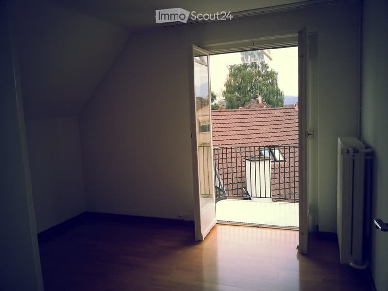 empty room with wooden floor, open door leading to balcony, radiator on the wall