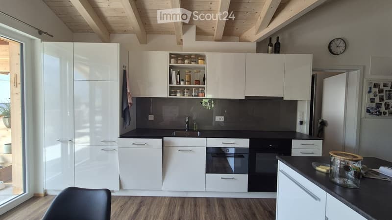 Modern kitchen with white cabinets, black countertops, and stainless steel appliances. Features include a sink, oven, and a clock on the wall.