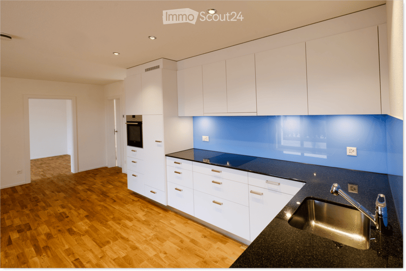 Modern kitchen with white cabinets, dark countertops, and a stainless steel sink. Features include a built-in oven and sleek, contemporary design.