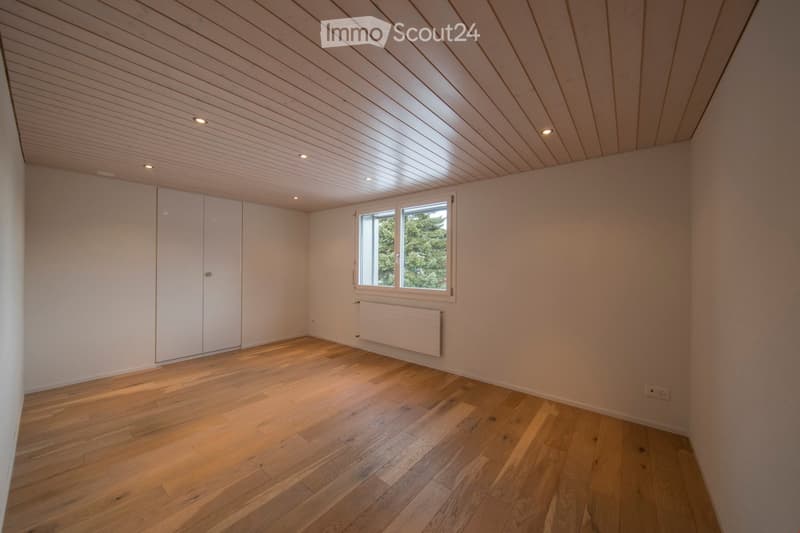 Empty room with wooden flooring, white walls, built-in closet, window with view, and recessed lighting.