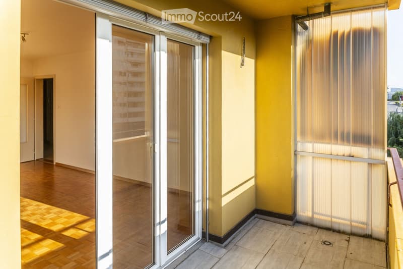 Balcony with sliding glass doors, yellow walls, wooden floor, and tiled balcony floor.