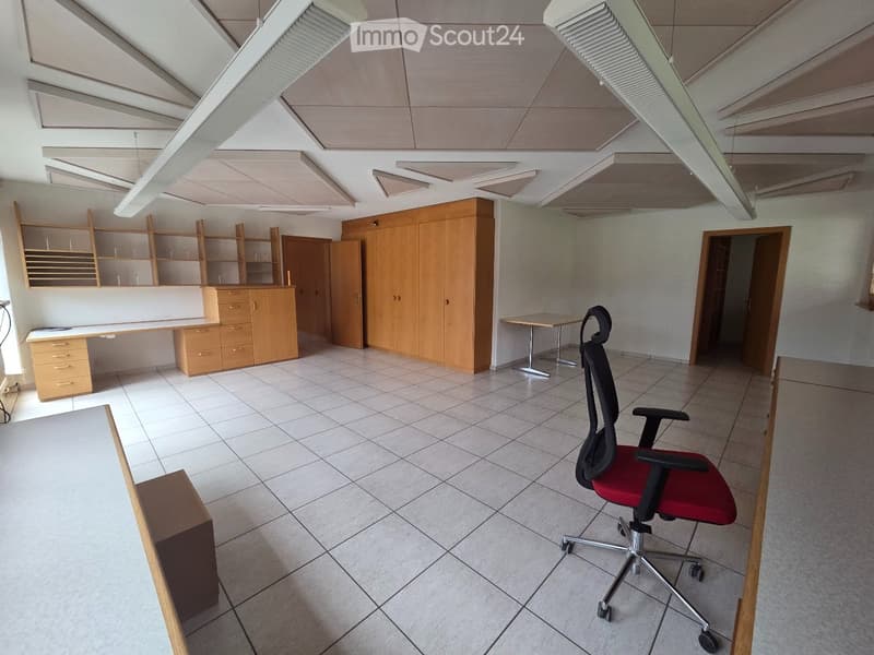 Office space with tiled floor, wooden cabinetry, shelves, a desk, and a red office chair.