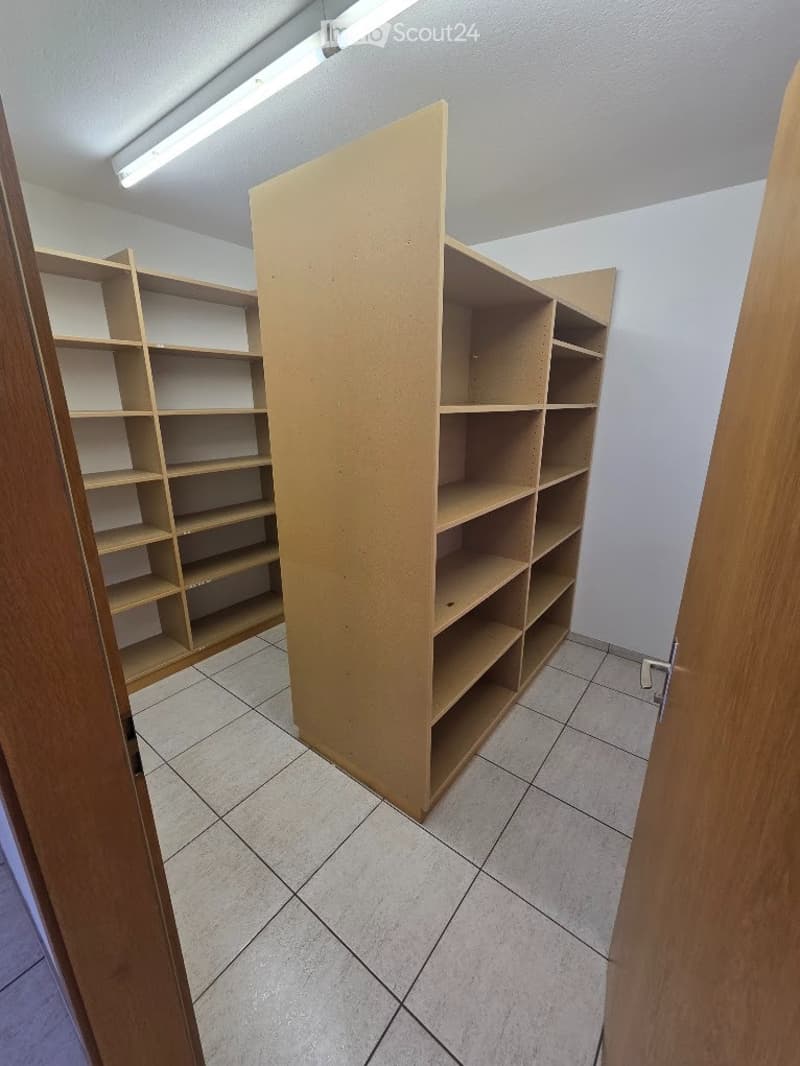 Empty room with tiled floor, white walls, and built-in wooden shelving units.