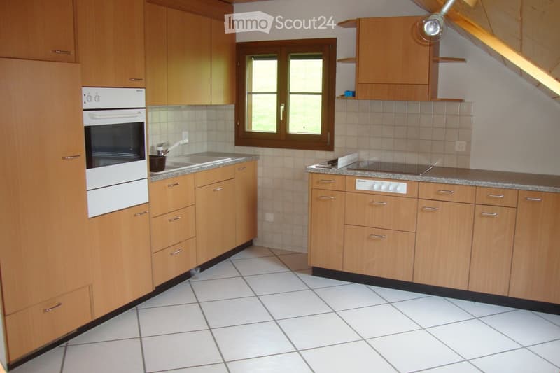 Modern kitchen with light wooden cabinets, white tiled floor, granite countertops, and stainless steel appliances including an oven, stove, and sink.