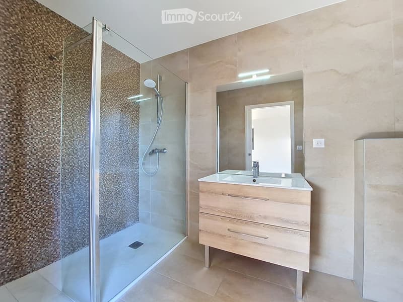 Modern bathroom with a glass-enclosed shower, a wooden vanity with a double sink, and a large mirror above the sink.