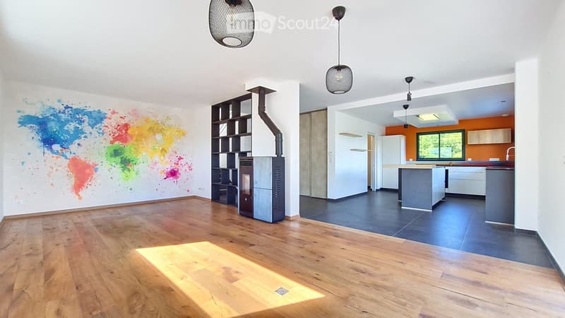 Open-plan living and kitchen area with wooden flooring, a colorful world map mural, a fireplace, shelves, a kitchen island, and modern kitchen cabinets.