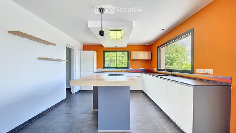 Modern kitchen with white cabinets, a central island, and orange accent walls. Features include a sink, faucet, and built-in shelves.
