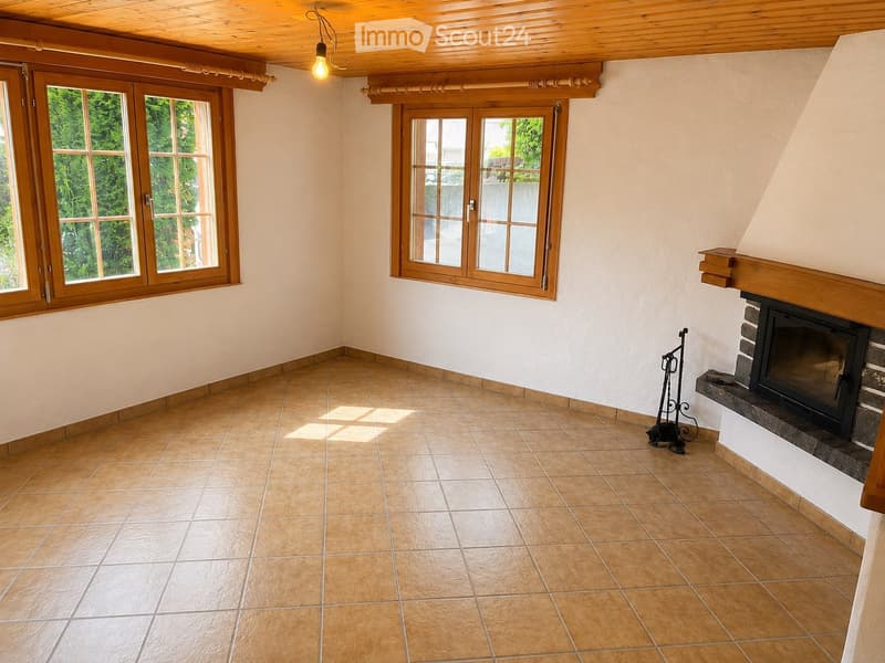 Empty room with tiled floor, wooden ceiling, large windows, and a fireplace with a wooden mantel.