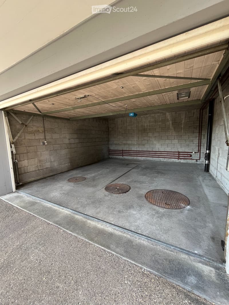 {"type": "Garage", "objects": [], "description": "Underground garage with concrete floor, brick walls, and three manhole covers. Exposed ceiling with wooden panels and metal beams.", "localized_descriptions": {"EN": "Underground garage with concrete floor
