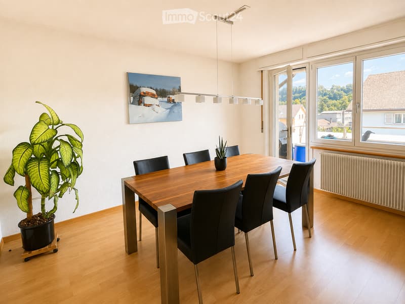 Bright dining room with wooden floor, large windows, modern pendant light, dining table with six chairs, potted plant, and artwork on the wall.
