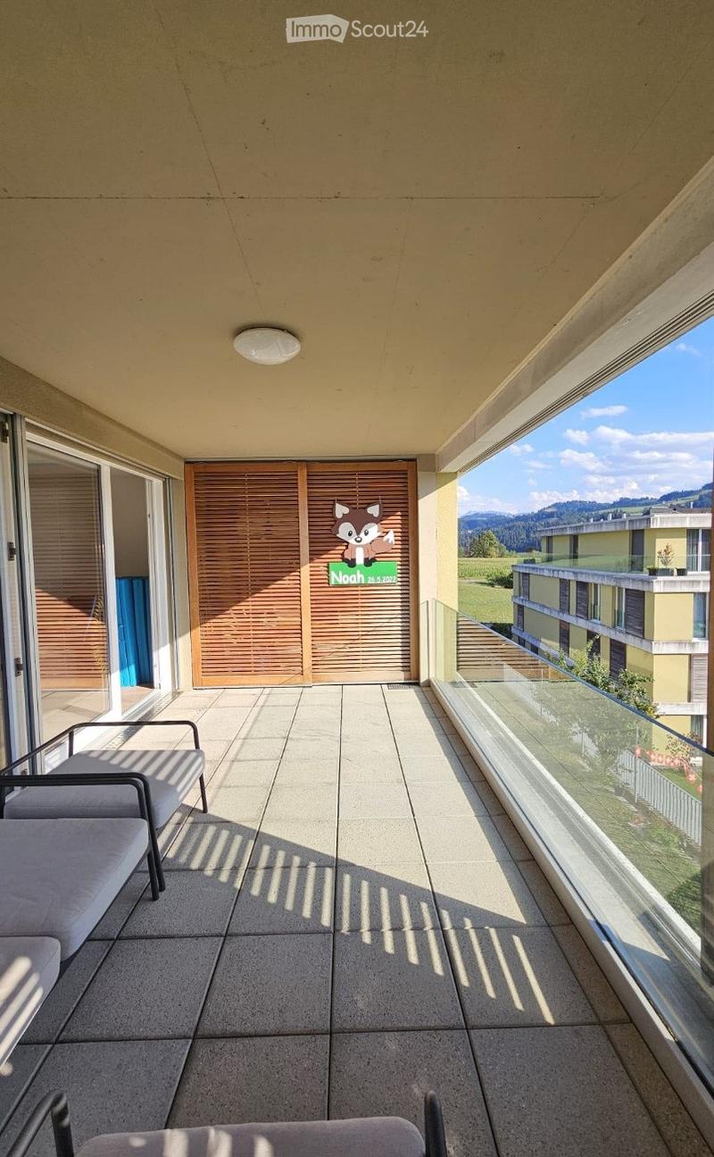 Balcony with tiled floor, glass railing, and scenic mountain view. Features a single chair and a decorative sign.