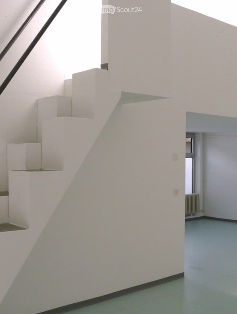 Modern, minimalist hallway with white walls, a staircase featuring white geometric steps, and a visible room at the end with a radiator and window.