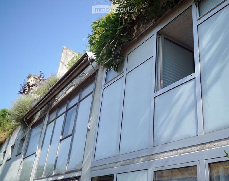 Modern building facade with large glass windows and a green rooftop garden.