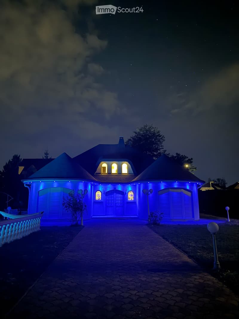 blaue Hausbeleuchtung abends - Sicht vom Haupttor