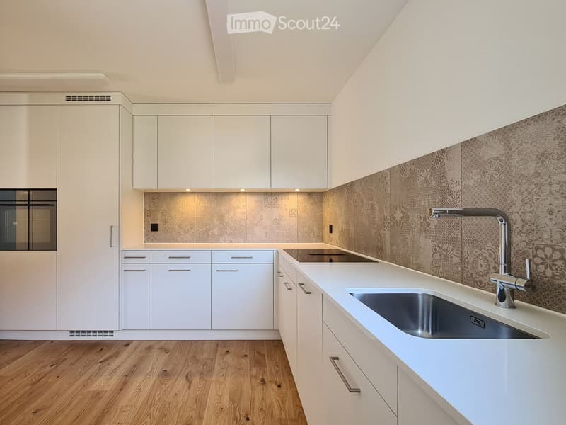 modern kitchen with wooden floor, white cabinets, integrated appliances, stainless steel sink, ceramic tile backsplash