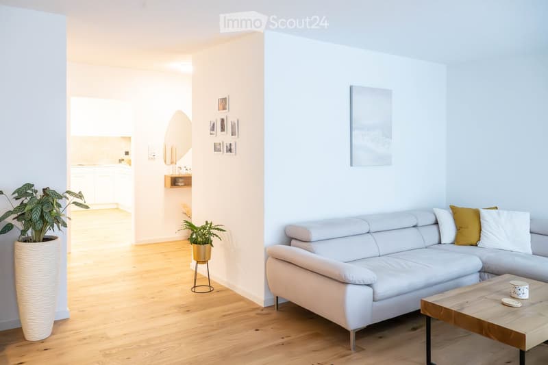 white sectional sofa, wooden coffee table, two potted plants, kitchen entrance