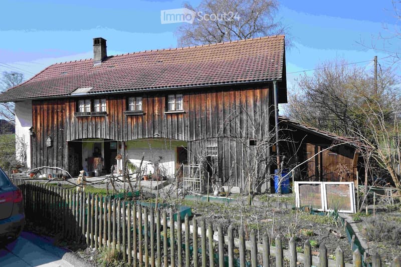 Old wooden house, red roof, wooden walls, chimney, windows, garden, fence, car parked
