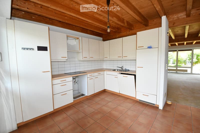 Bright kitchen with white cabinets, tiled walls, and a wooden ceiling. Features include a sink, faucet, dishwasher, and electric stove.
