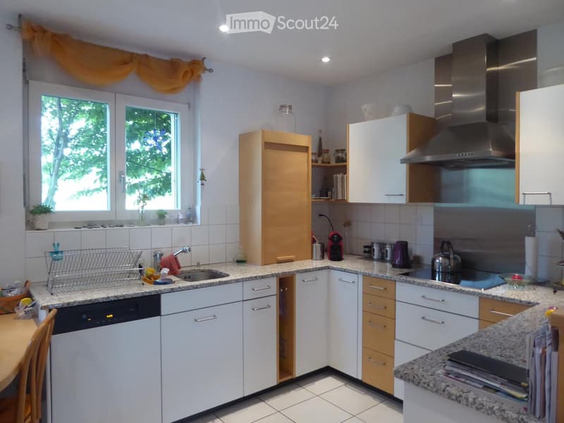 Modern kitchen with white cabinets, granite countertops, stainless steel appliances, and a large window with yellow curtains.